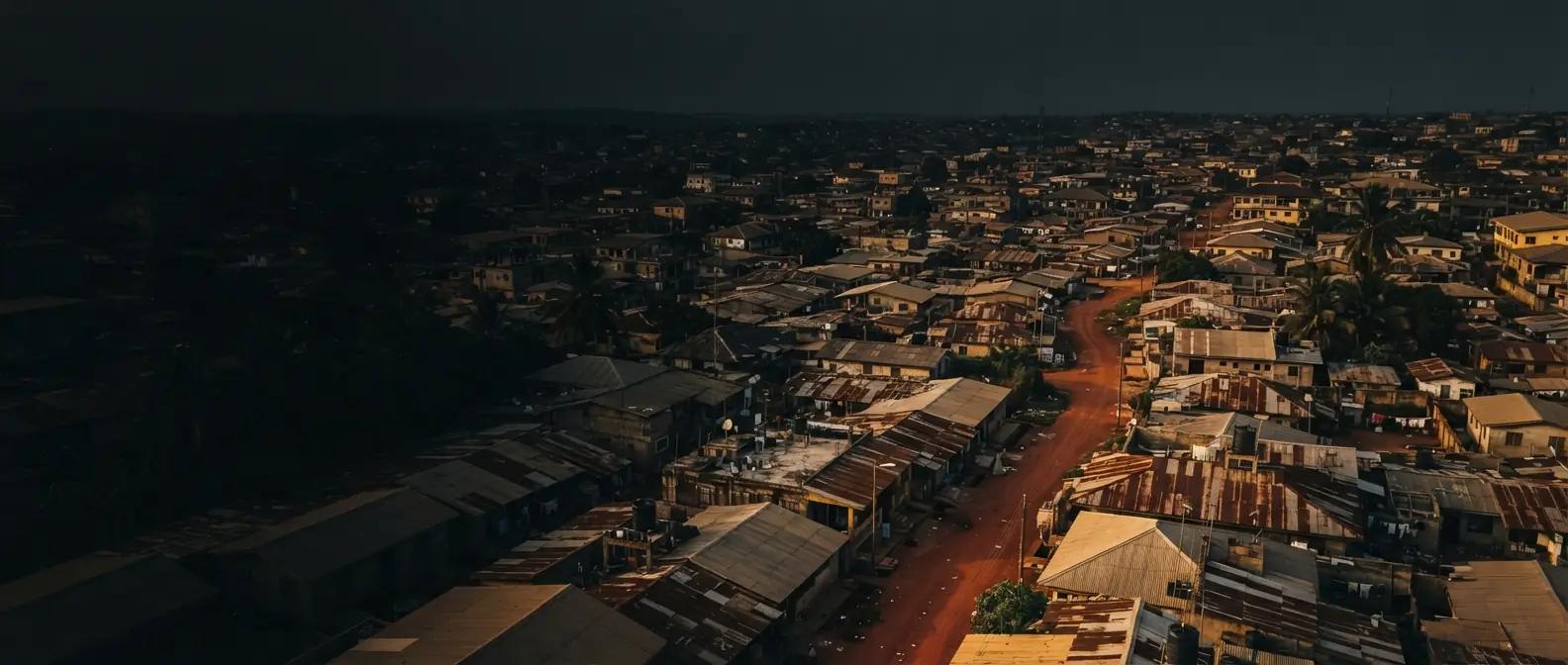 Aerial view of dense low-rise housing and unpaved roads in Ghana at dusk